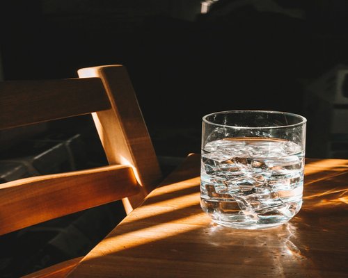 Glass of water with lemon on a wooden table